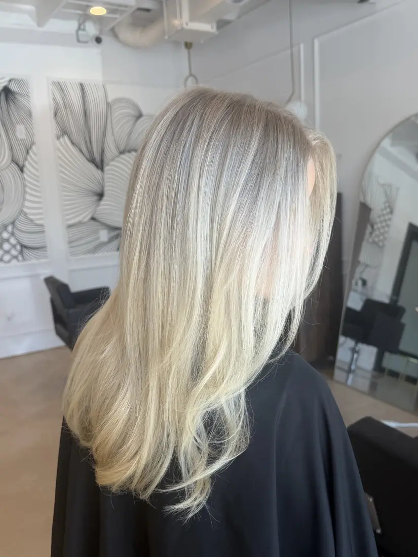Bright platinum hair worn straight and glossy, client in a black cape.